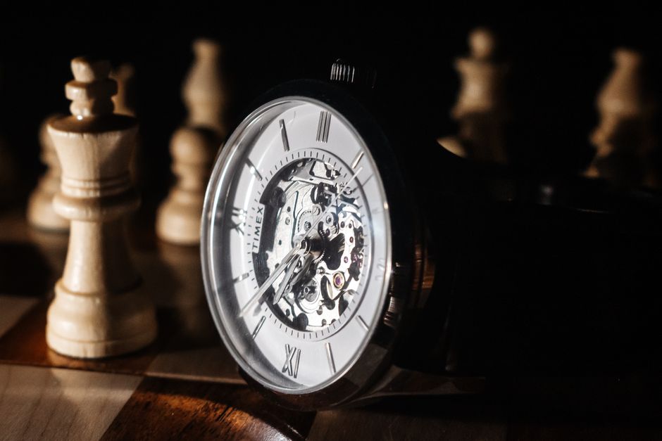 A detailed mechanical watch set against a chessboard with chess pieces.